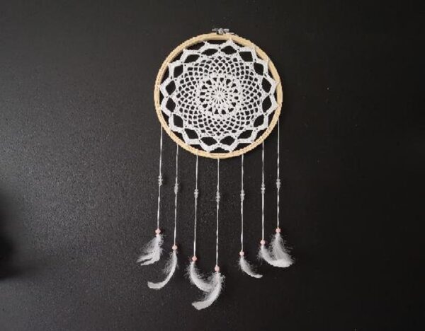 Handmade Crochet Round Wall Decoration With Feathers view from the front on the black wall